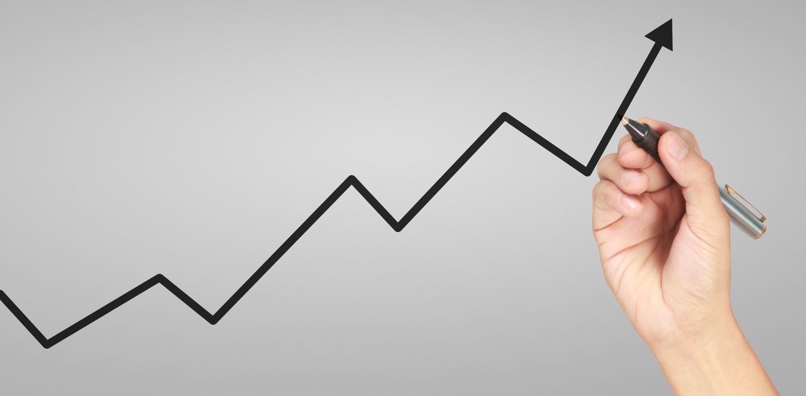 Hand drawing a trend line on a rising stock chart