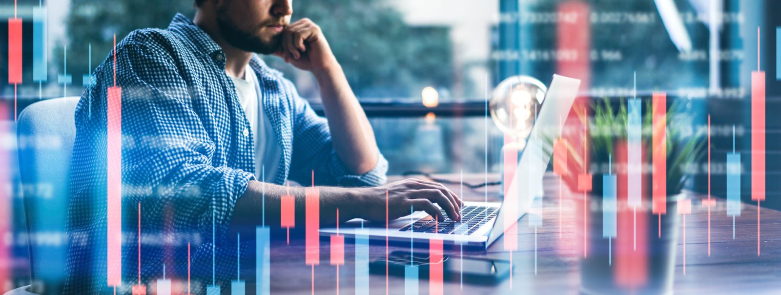 Businessman at office desk reacting to red and green candlestick chart on screen